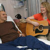  A music therapist plays guitar for a hospital patient.
