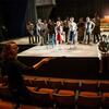 A female student is directing actors on stage.