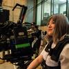 A film student sitting among film equipment in a film studio on campus.