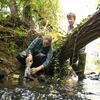 Temple student and professor in a river bed taking water samples.