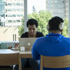 Two students work in front of a window in Charles Library.