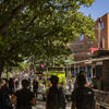four students walk by Temple food trucks on a sunny day.