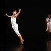 A dancer leaps on stage, with another standing behind her. 